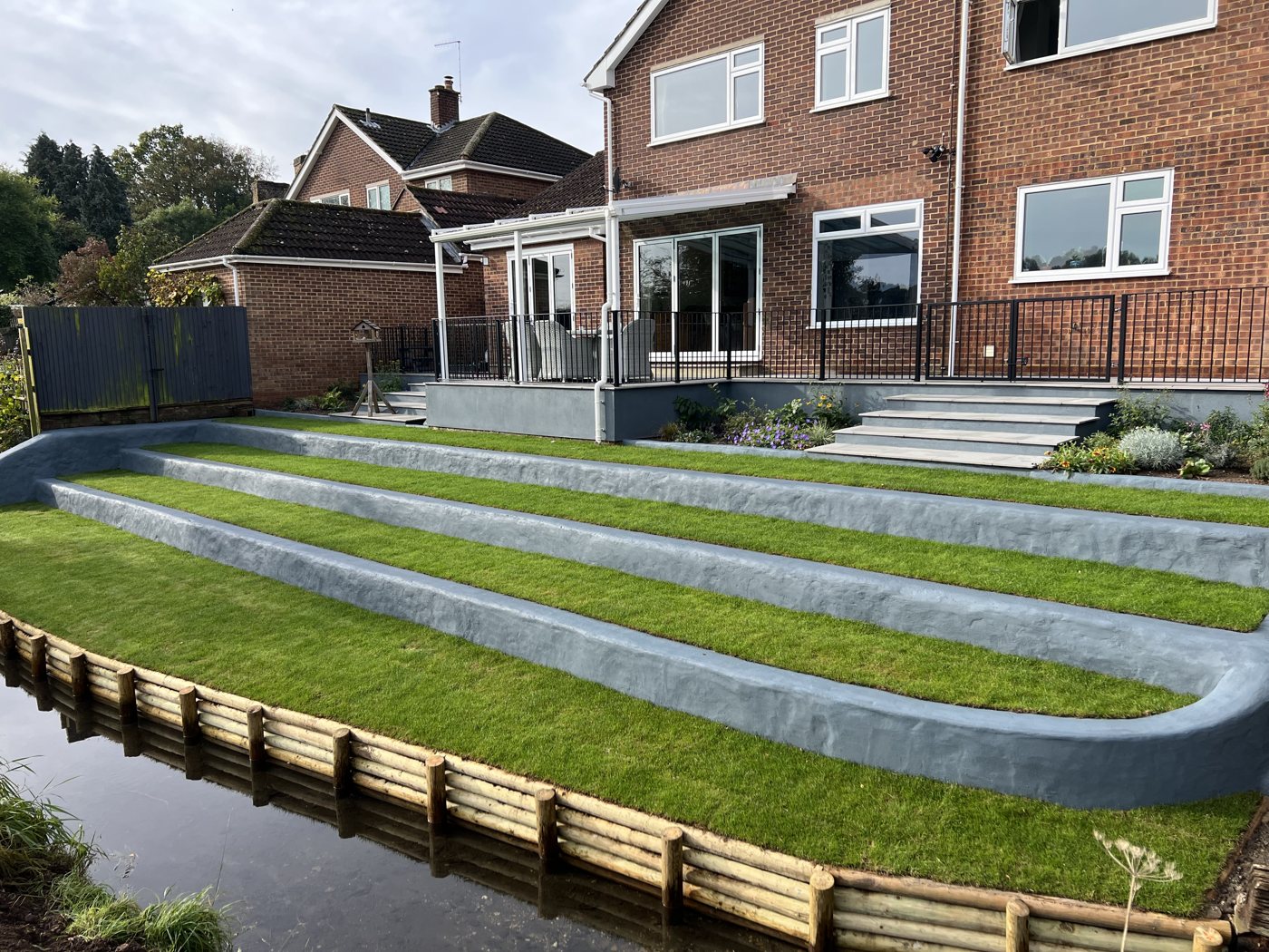 Terraced landscaped garden with tiered lawns and rendered retaining walls in Hertford